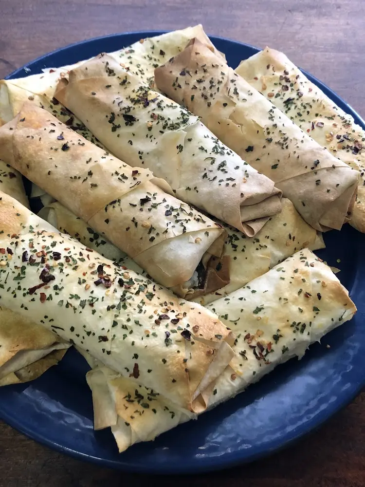 Plate of freshly baked sigara böreği sprinkled with herbs and chilli